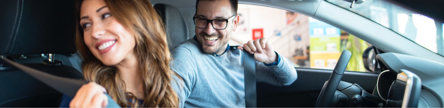 Woman And Man Smiling And Putting On Seatbelts