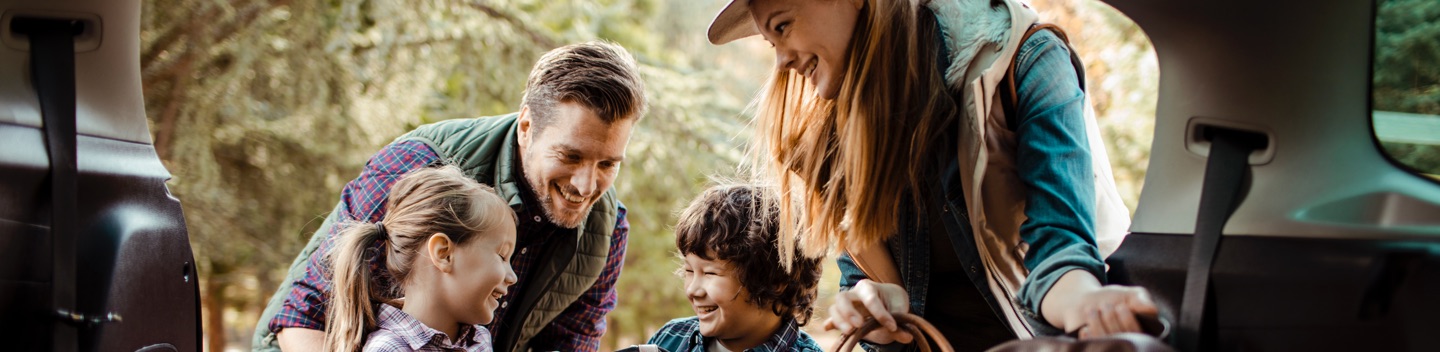 Young, Smiling Family Engaging With Luggage