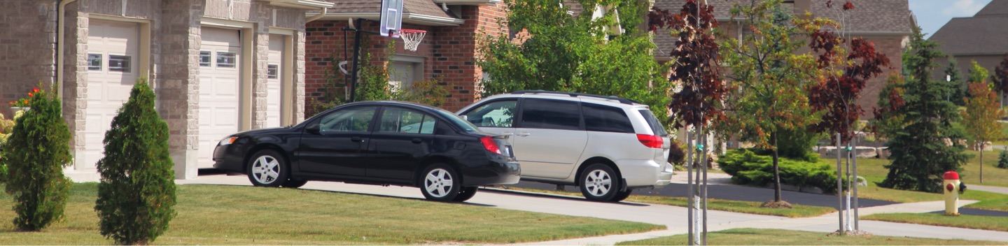 Vehicles Parked In Driveway Of Home In Residential Neighborhood