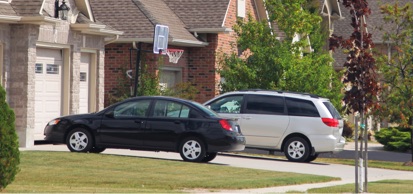 Vehicles Parked In Driveway Of Home In Residential Neighborhood