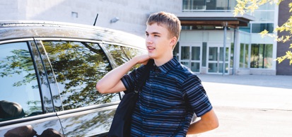 Student Holding Bag Standing Next To Car