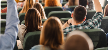 Students Raising Hands In Lecture Hall